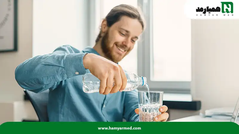 مردی پس از پاسخ به سوال چگونه پوست صاف داشته باشیم در حال مصرف آب است